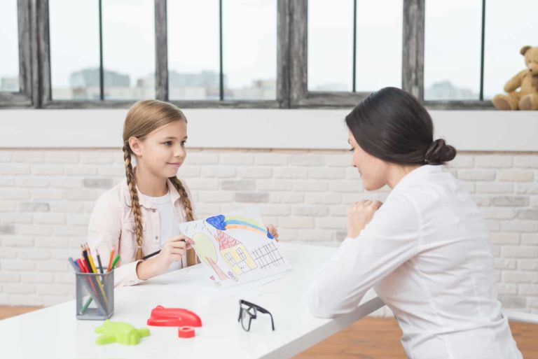 little blonde girl showing drawn house paper her female psychologist